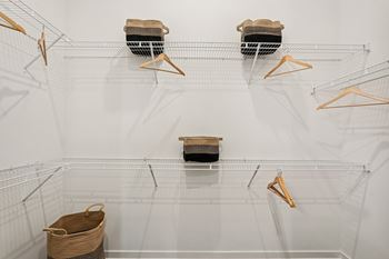 A white wire shelving unit with three shelves and four hangers